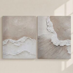 Díptico de cuadros abstractos de estilo wabi-sabi y marinos pintados a mano con texturas en relieve blancas y fondo beige arena claro, expuestos en una pared minimalista con sombras de luz natural