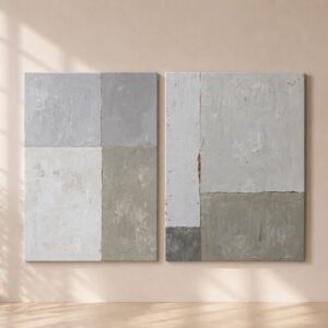 Díptico de cuadros abstractos asimétricos en tonos blancos, grises y beige sobre pared de salón moderno con luz natural.